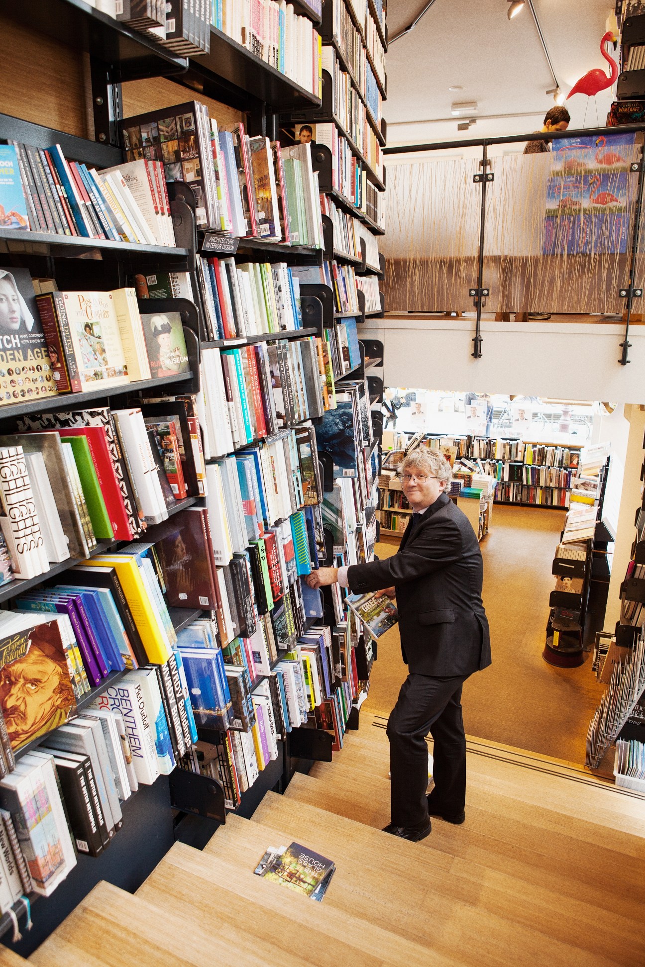 Lynn Kaplanian browses books on black shelving at The American Book Center in Amsterdam.
