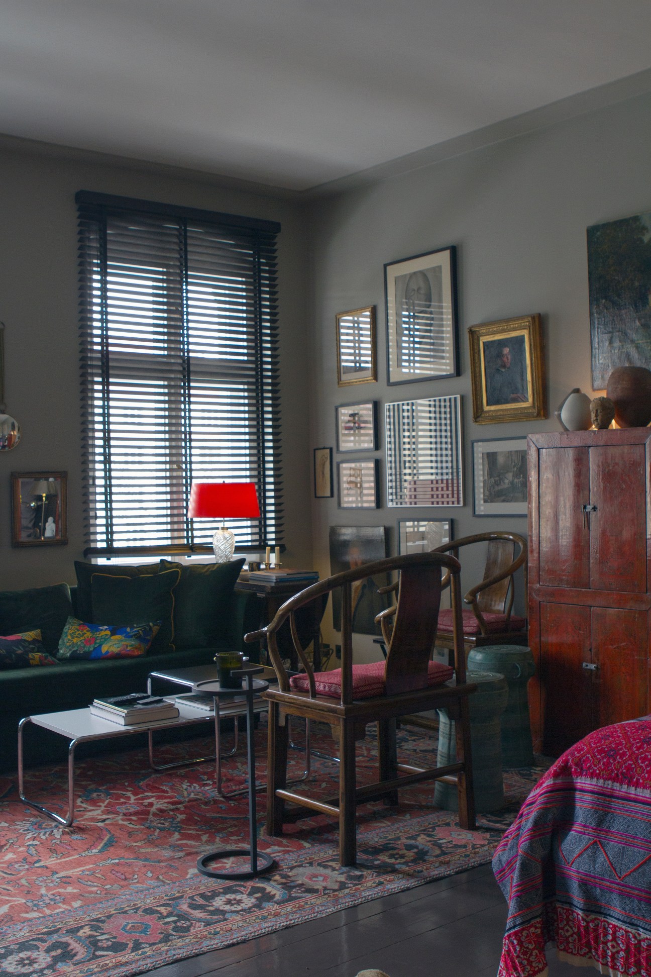 Interior of Berlin apartment with dark sofa, wooden chairs, gallery wall, and shuttered windows.