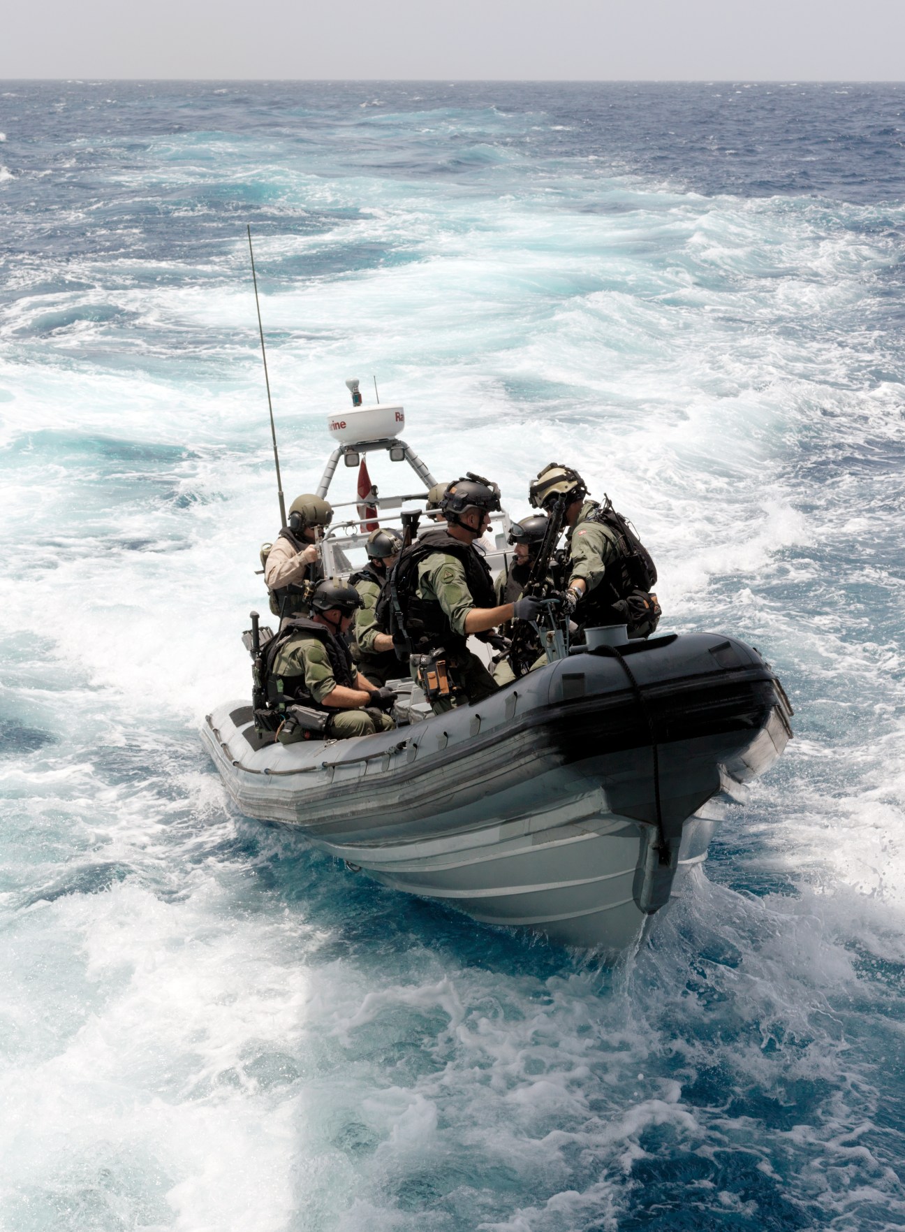 Danish special forces Frogmen in military gear operate a rigid inflatable boat in rough ocean waters.