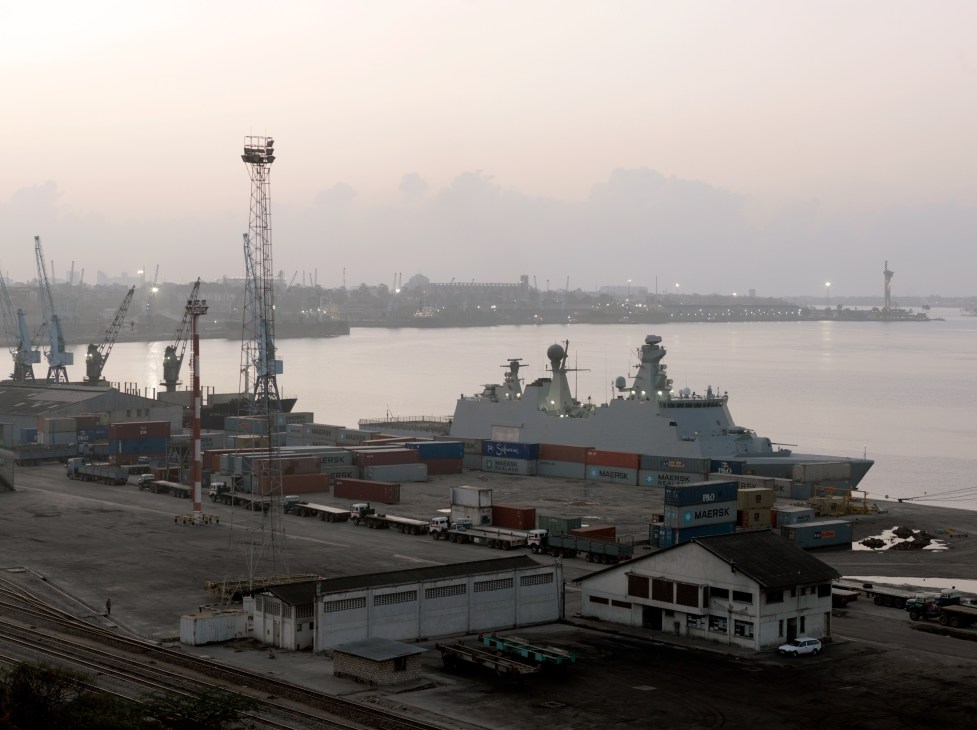 Danish Navy warship HDMS Absalon docked at Mombasa port with shipping containers and industrial cranes.