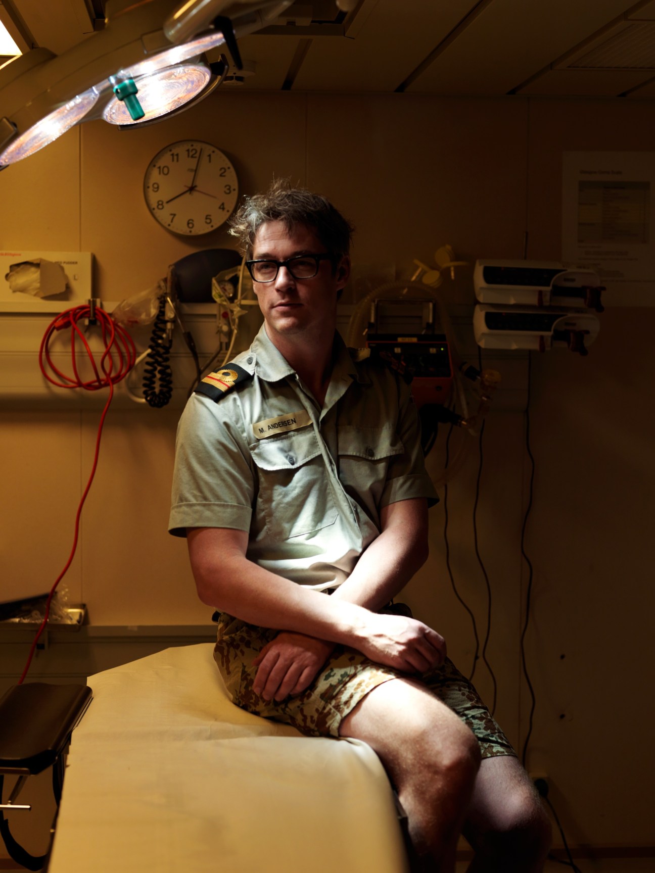 Dr Mads Andersen, ship's doctor, seated in medical bay wearing military uniform and glasses.