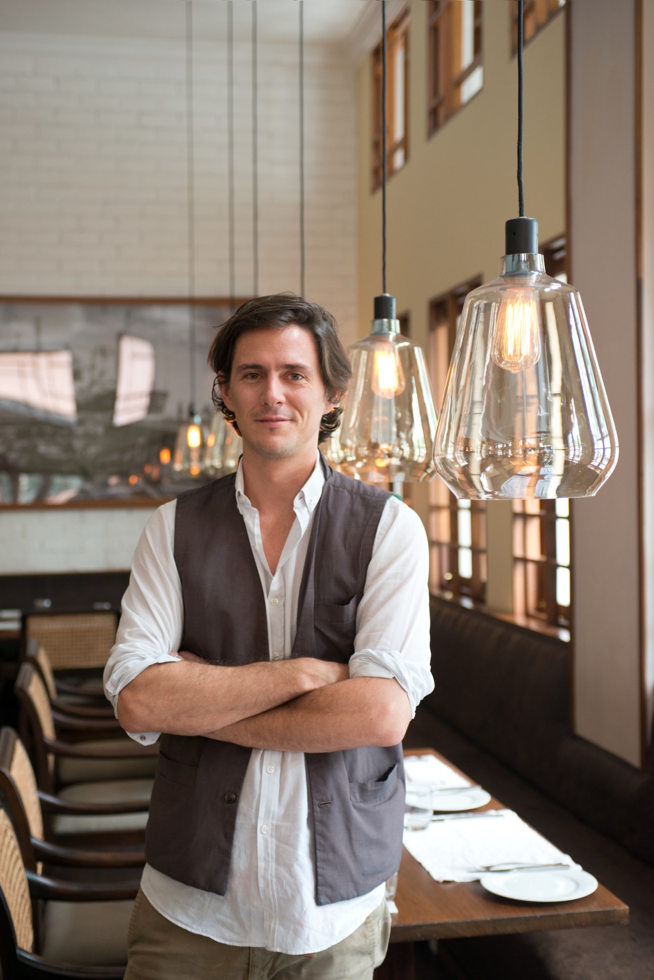 Nico Elliott, founder of Union Bar and Grill, stands in a modern restaurant interior with pendant lights.