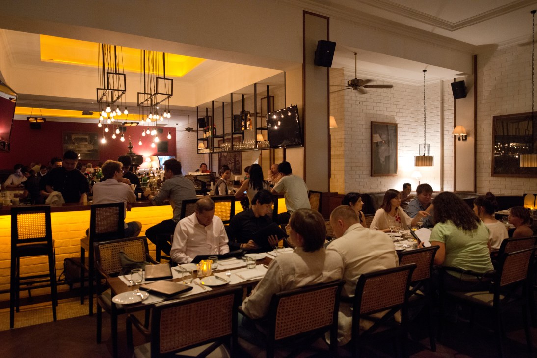 Diners seated at tables in Union Bar and Grill's contemporary restaurant space with glowing yellow bar and pendant lighting.