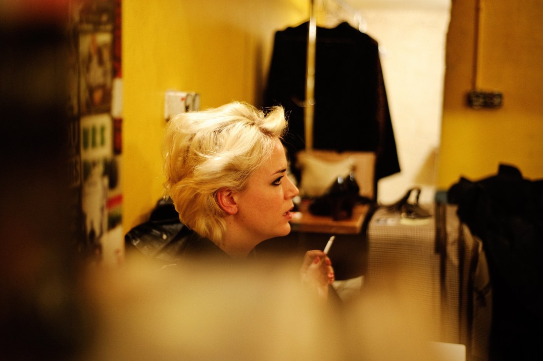 Swedish singer-songwriter Frida Hyvönen signing an autograph backstage in a yellow room.