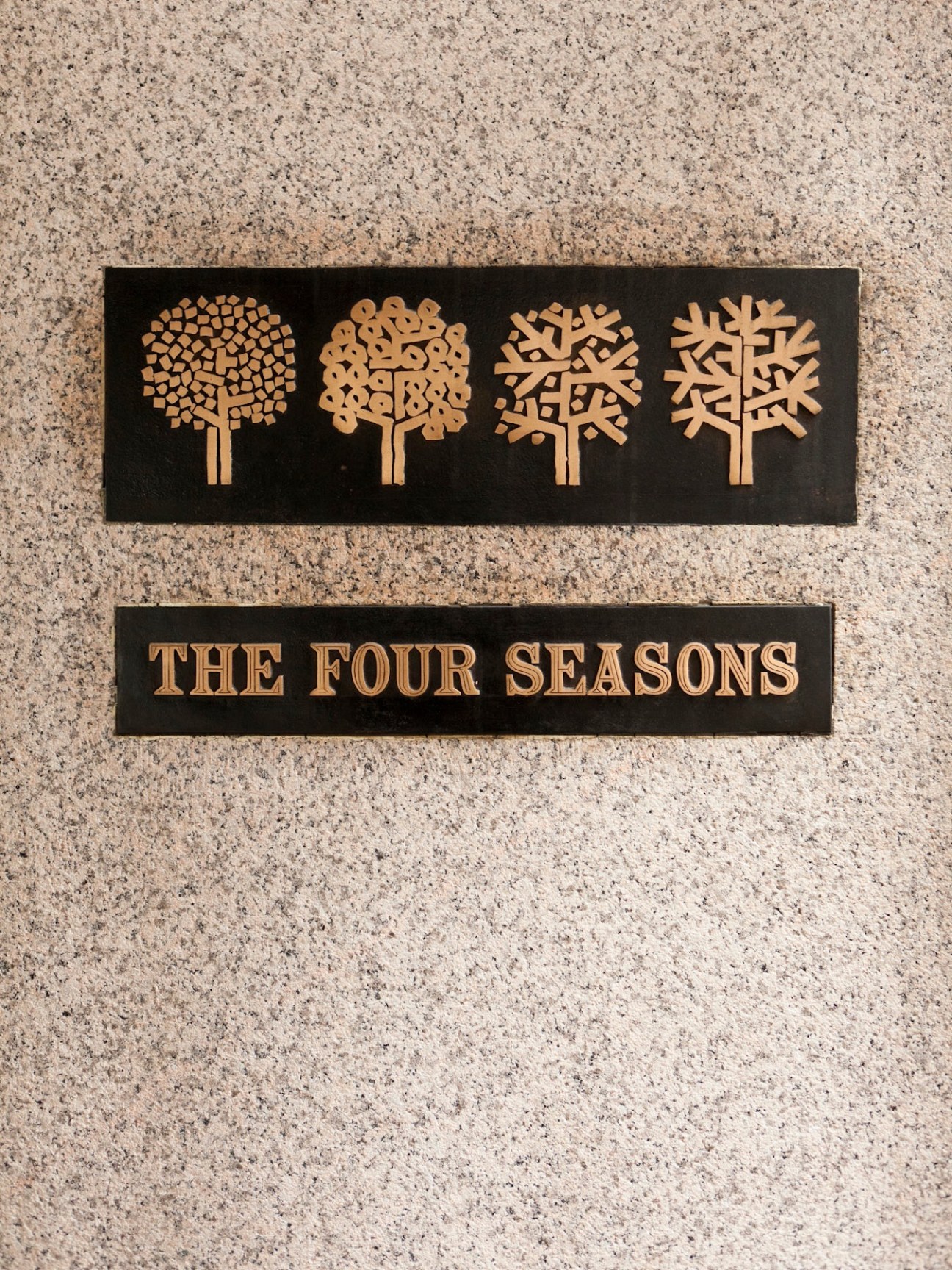 The Four Seasons restaurant logo featuring four stylized trees representing seasons in gold on black plaques.