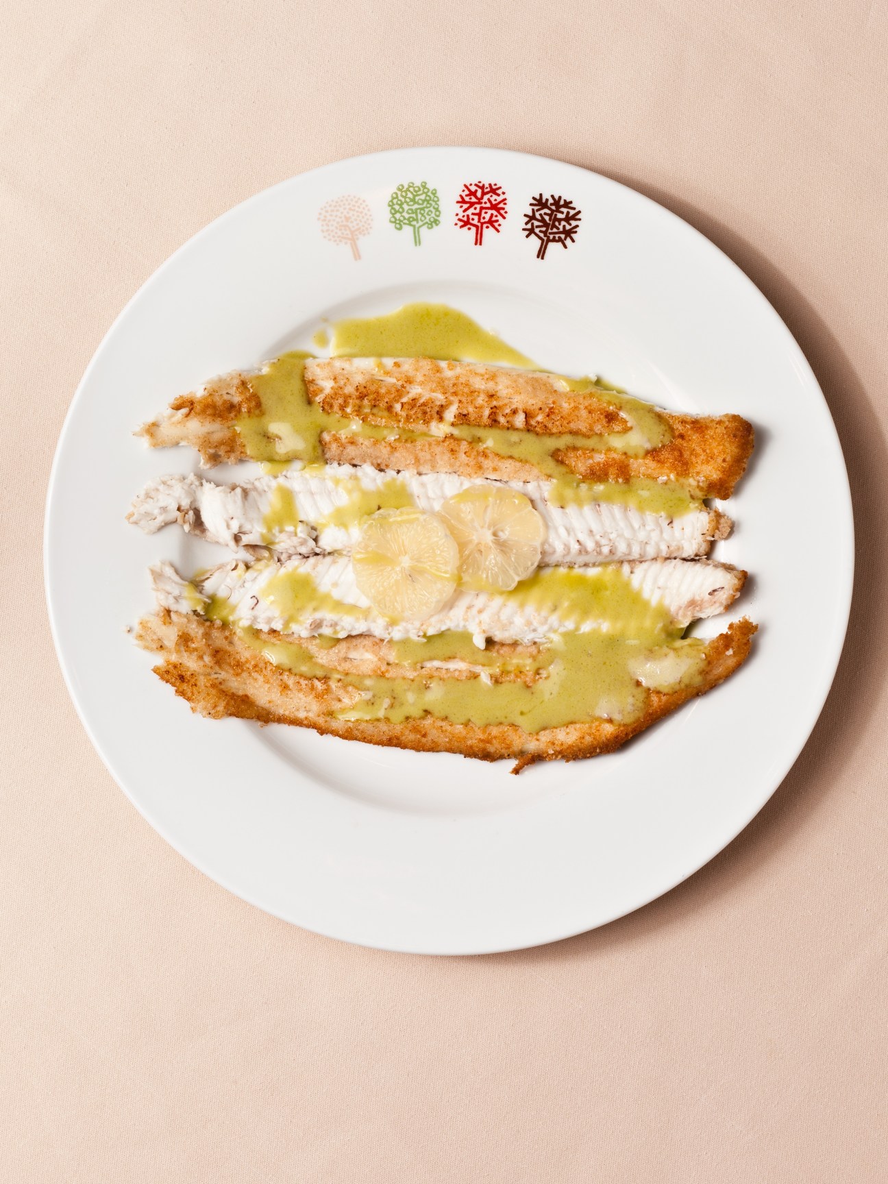 Dover sole with key lime sauce plated on white dish with Four Seasons seasonal tree logo.