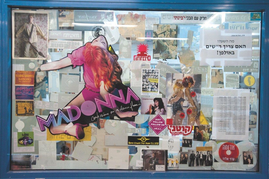 A blue-framed window display decorated with music posters, album covers, band photographs and colorful artwork at Galgalatz radio station.