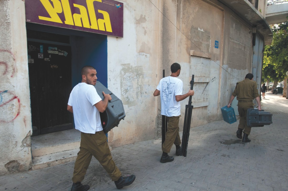 Israeli soldiers carrying audio equipment cases outside the Galgalatz radio station building.
