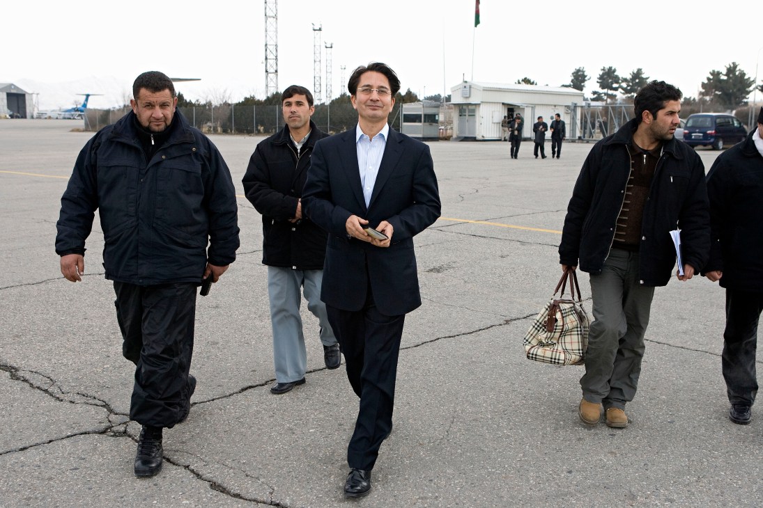 Said Jawad, Afghan ambassador to Washington, walks across an airport tarmac with security personnel and colleagues.