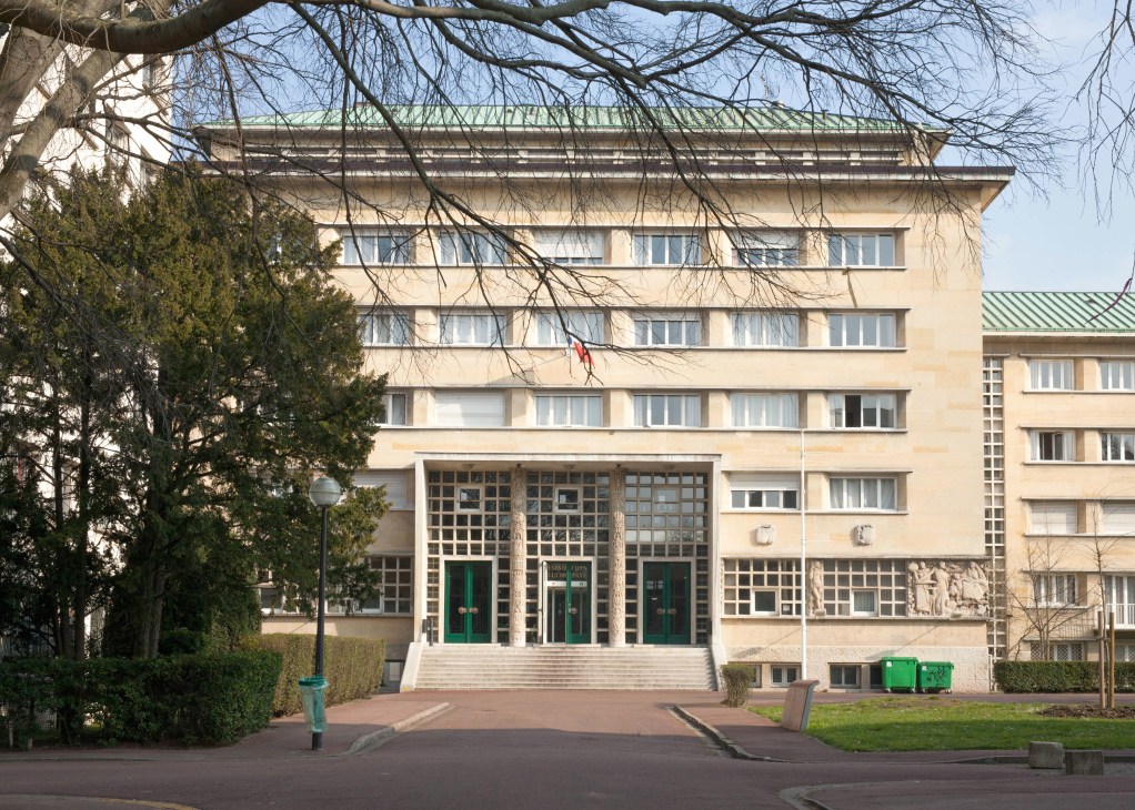 The Fondation Lucien Paye building with cream-colored facade, green roof detail, and green entrance doors at the Cité Internationale Universitaire de Paris.