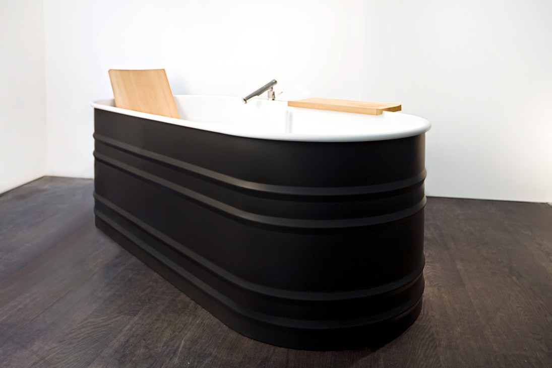Modern bathtub with black exterior, white interior rim, wooden backrest and shelf by Agape design.
