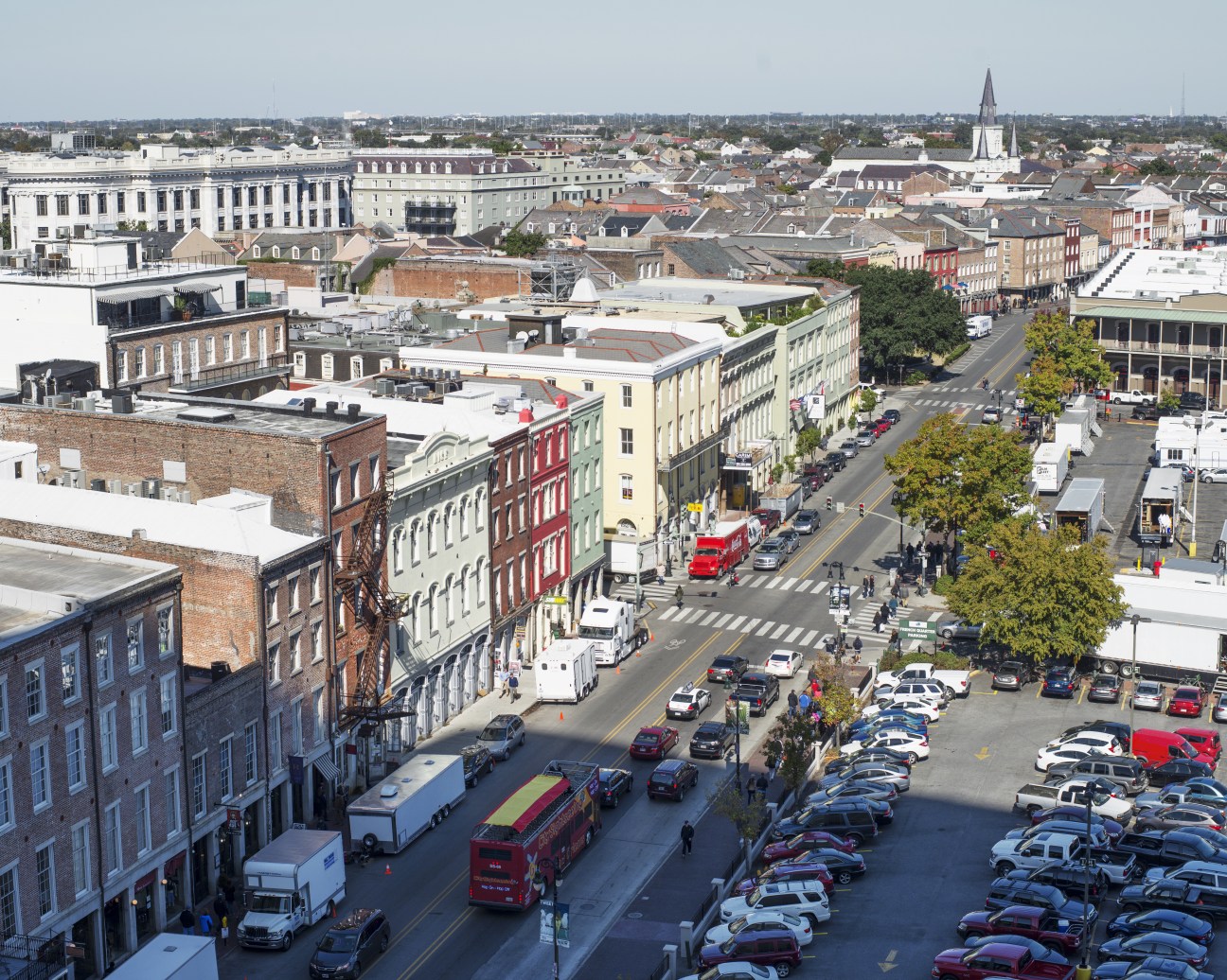 Aerial view of New Orleans city streets with historic architecture, parked cars, and pedestrians.
