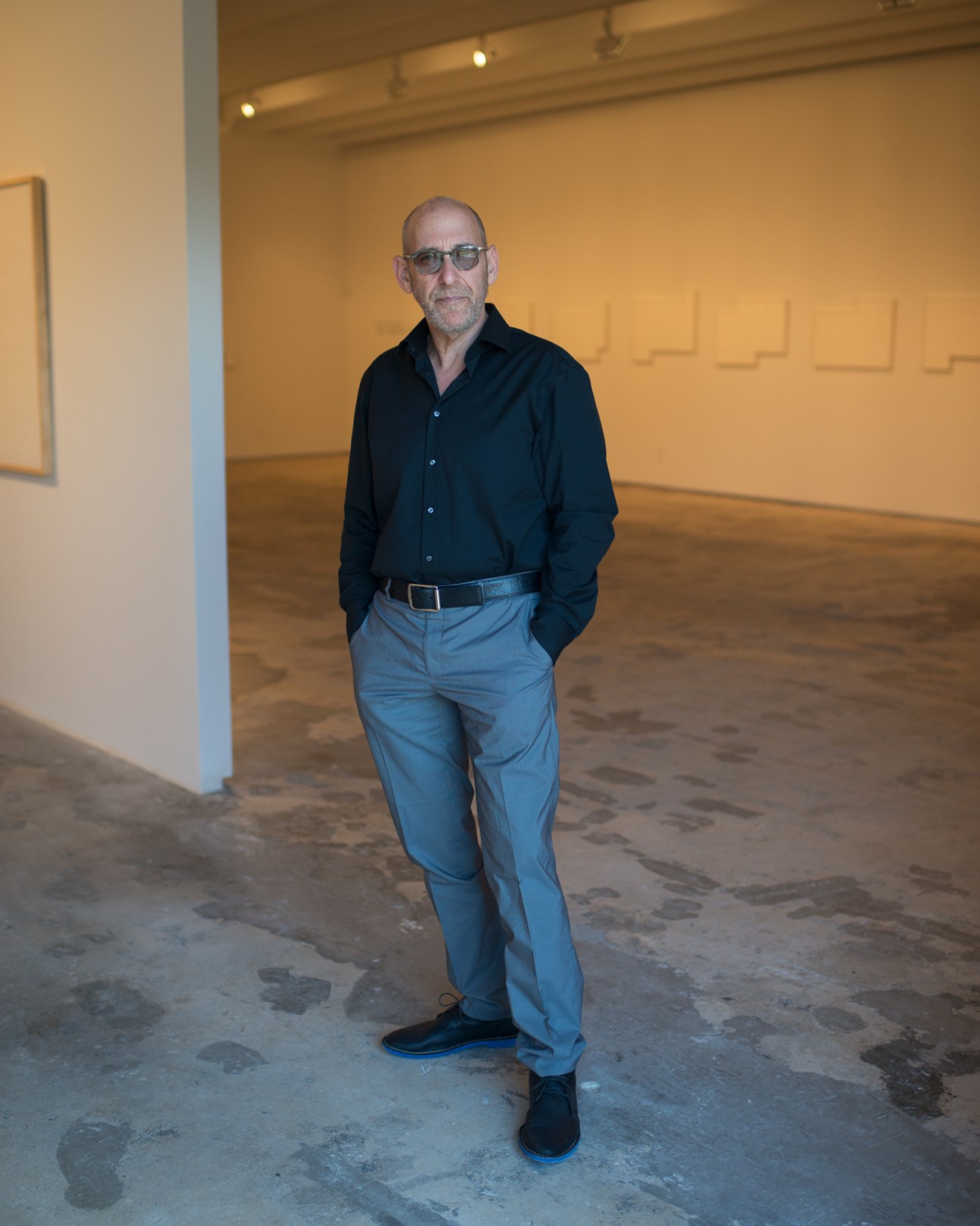 Fredric Snitzer stands in his white gallery space surrounded by artwork on the walls.