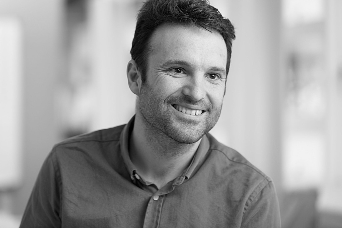 Portrait of Albert Hill, co-founder of The Modern House, smiling at the camera in black and white.