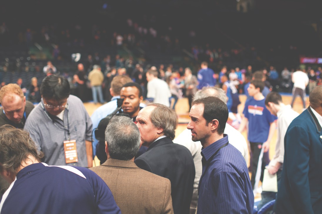 Sports journalists and officials conduct interviews on a basketball court before a game.
