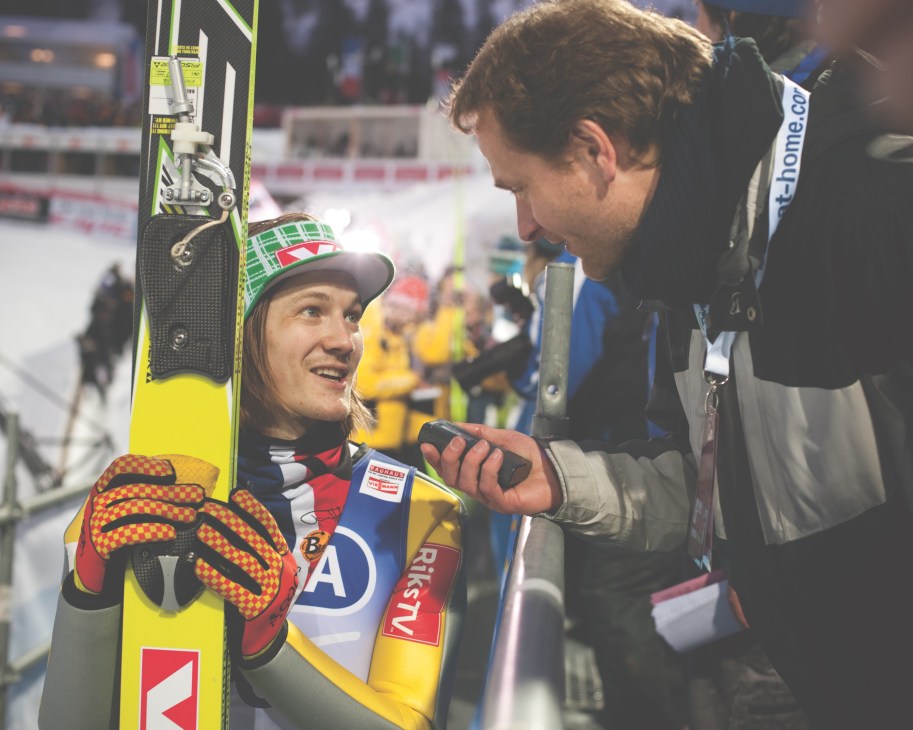 Journalist Thomas Hahn interviews Norwegian ski jumper Tom Hilde at a ski jumping competition.