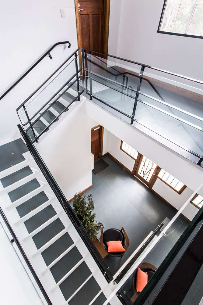 Overhead view of a modern stairwell with glass railings, wooden doors, and contemporary furnishings.