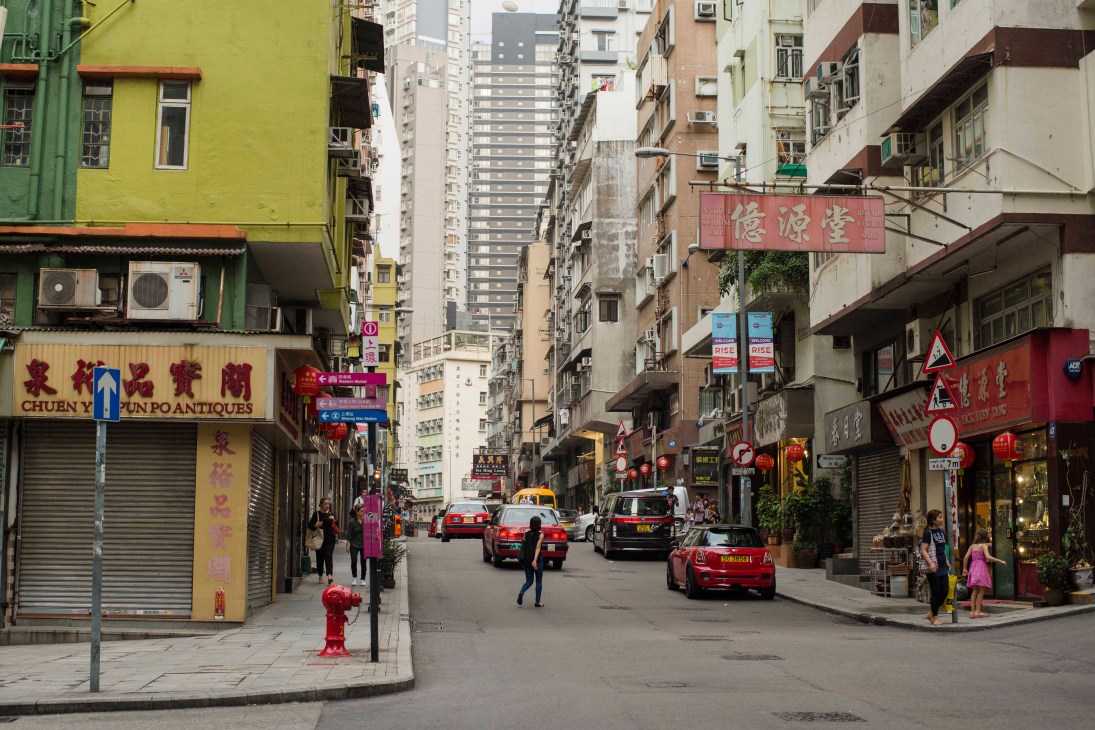 Hong Kong street scene with colorful buildings, shops, taxis and pedestrians on Hollywood Road.