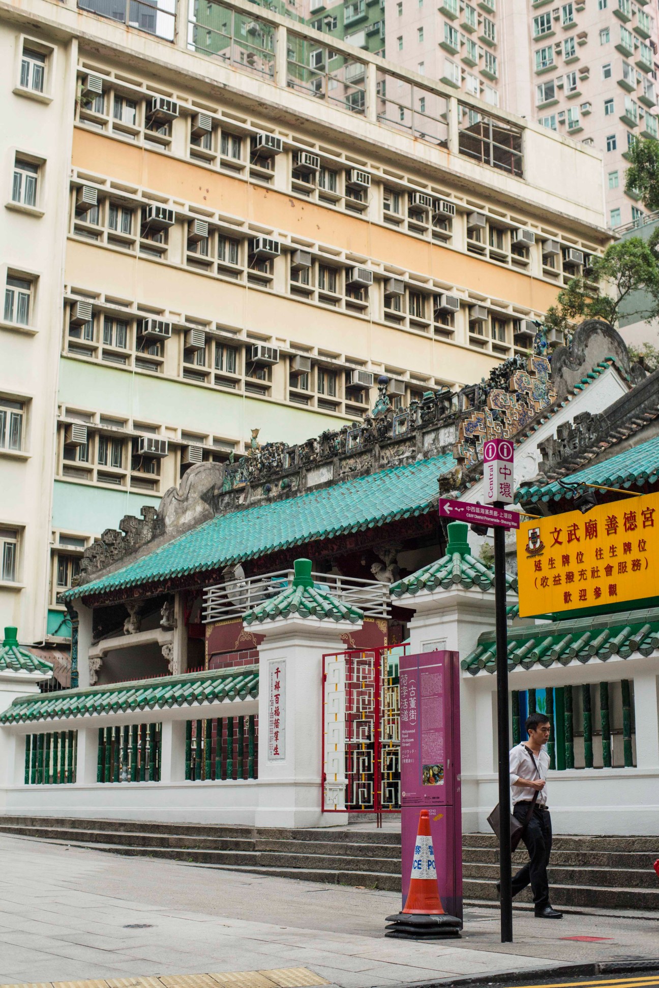 Man Mo Temple with traditional green-tiled roof and red doors beneath modern apartment buildings in Hong Kong.