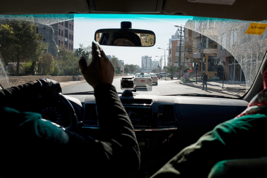 View from inside a car of journalists traveling through a street in Erbil with modern buildings lining the road.