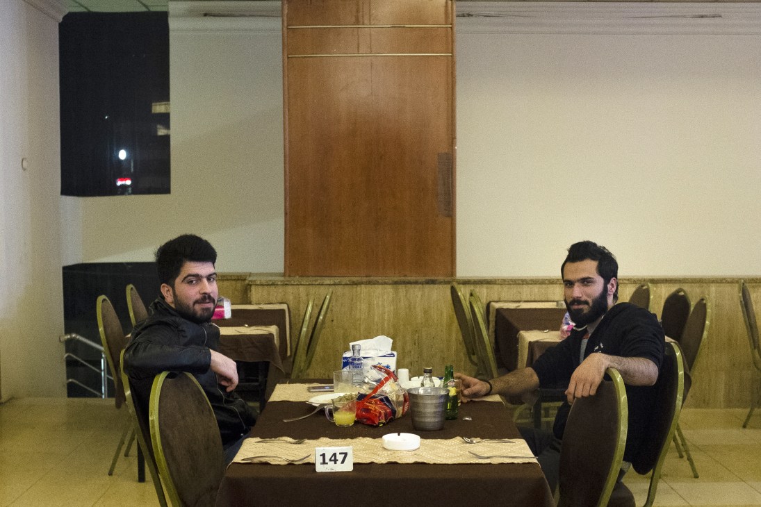 Two men sit at a table with food and drinks at the Teachers' Club restaurant in Erbil.