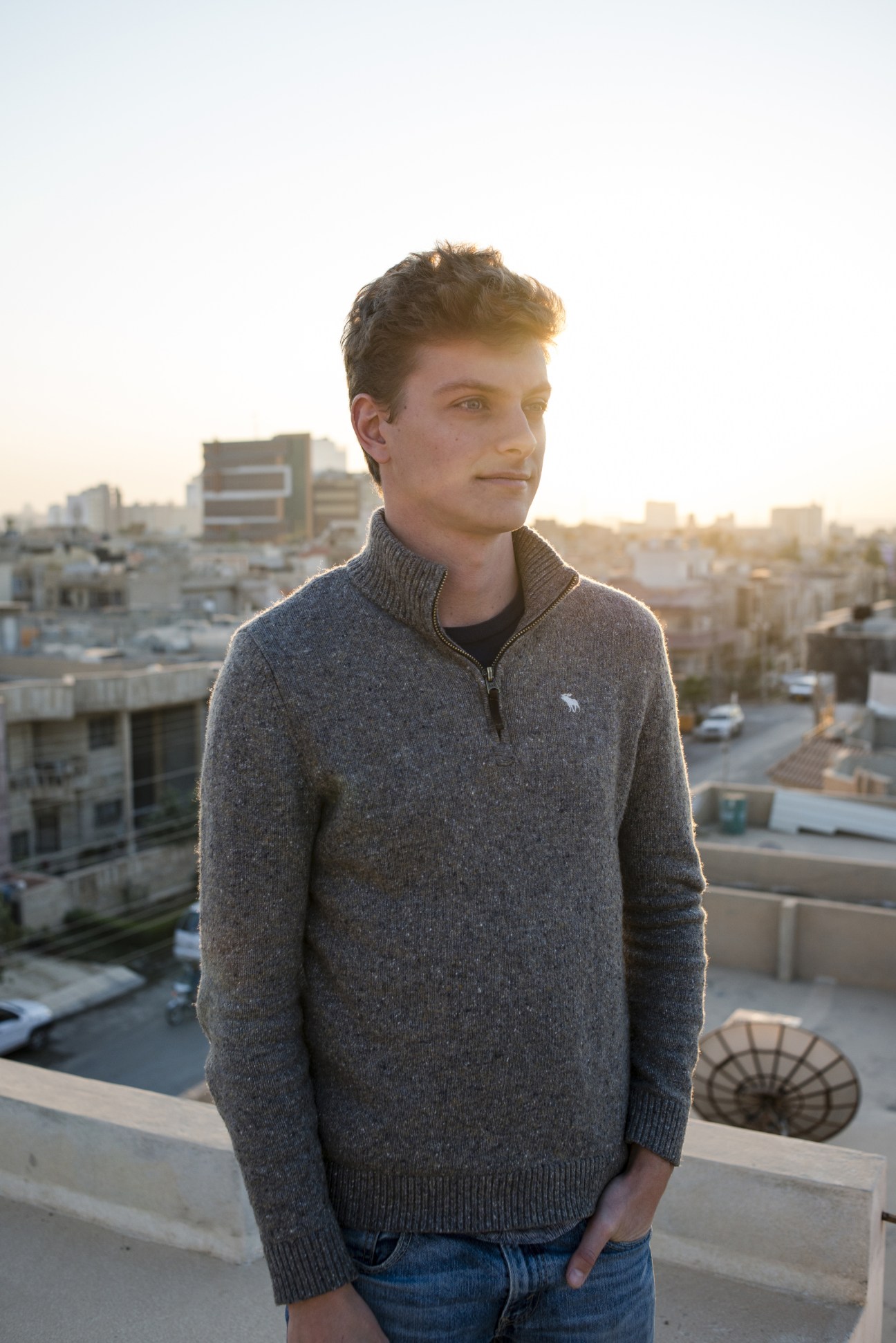 Belgian freelance reporter Wilson Fache stands on a rooftop overlooking Erbil's cityscape at sunset.