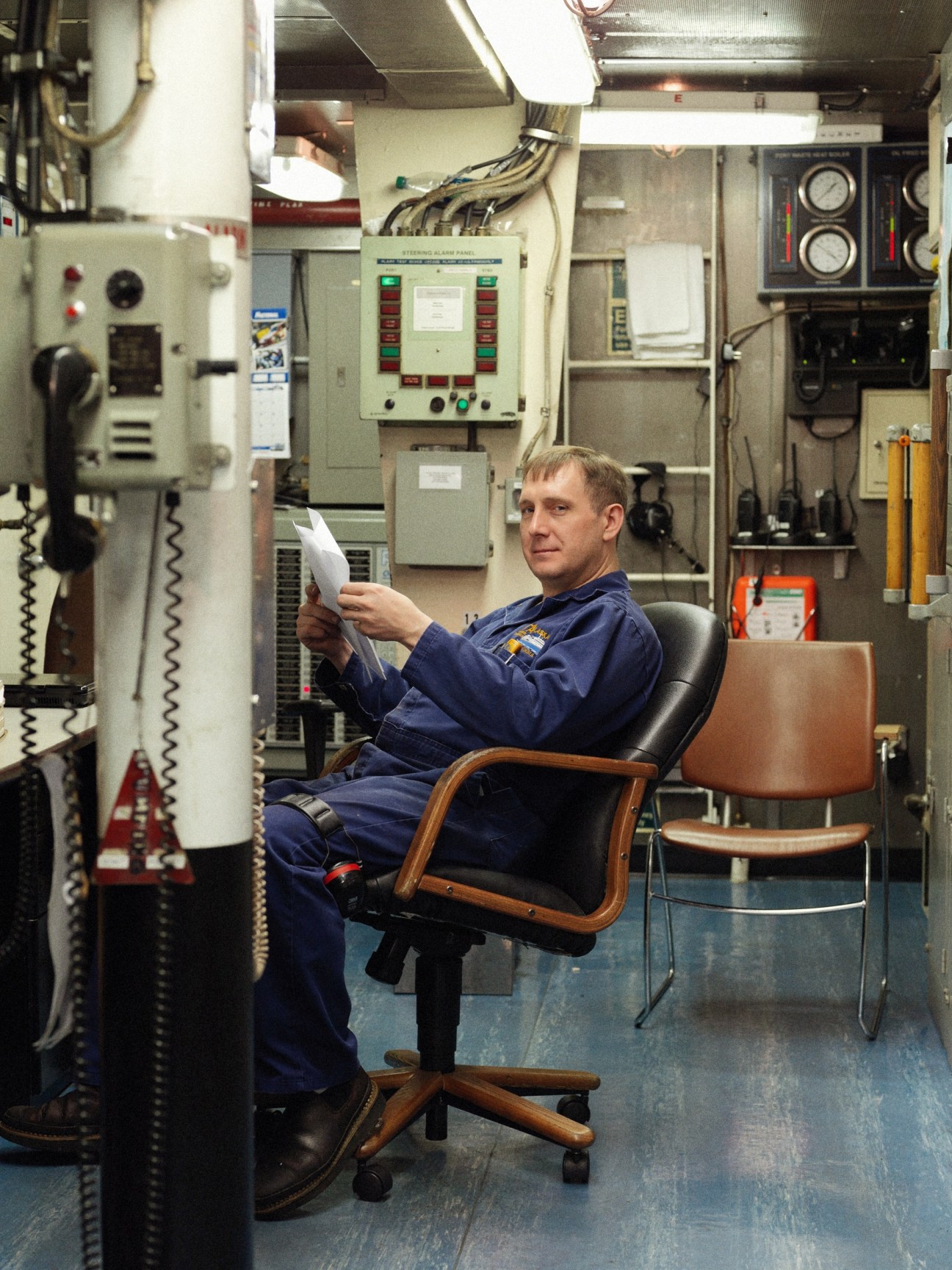 Engineer sits in control room of M/V Columbia ferry, surrounded by electrical panels and monitoring equipment.