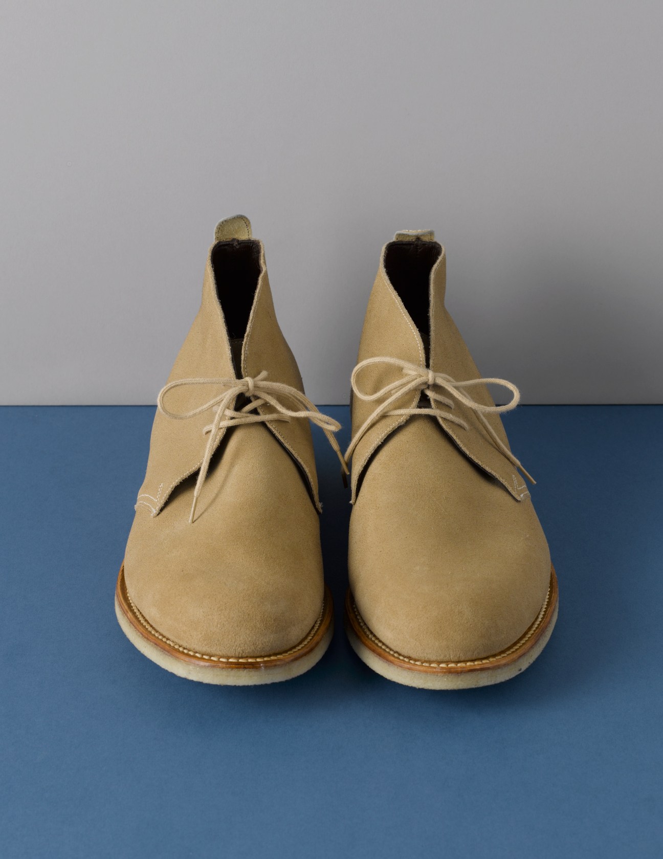 Pair of beige suede desert boots with crepe soles and lace-up closures by Albam and Grenson.