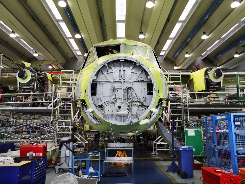 C-27J Spartan tactical airlifter undergoing assembly in a hangar with exposed fuselage and engines visible.