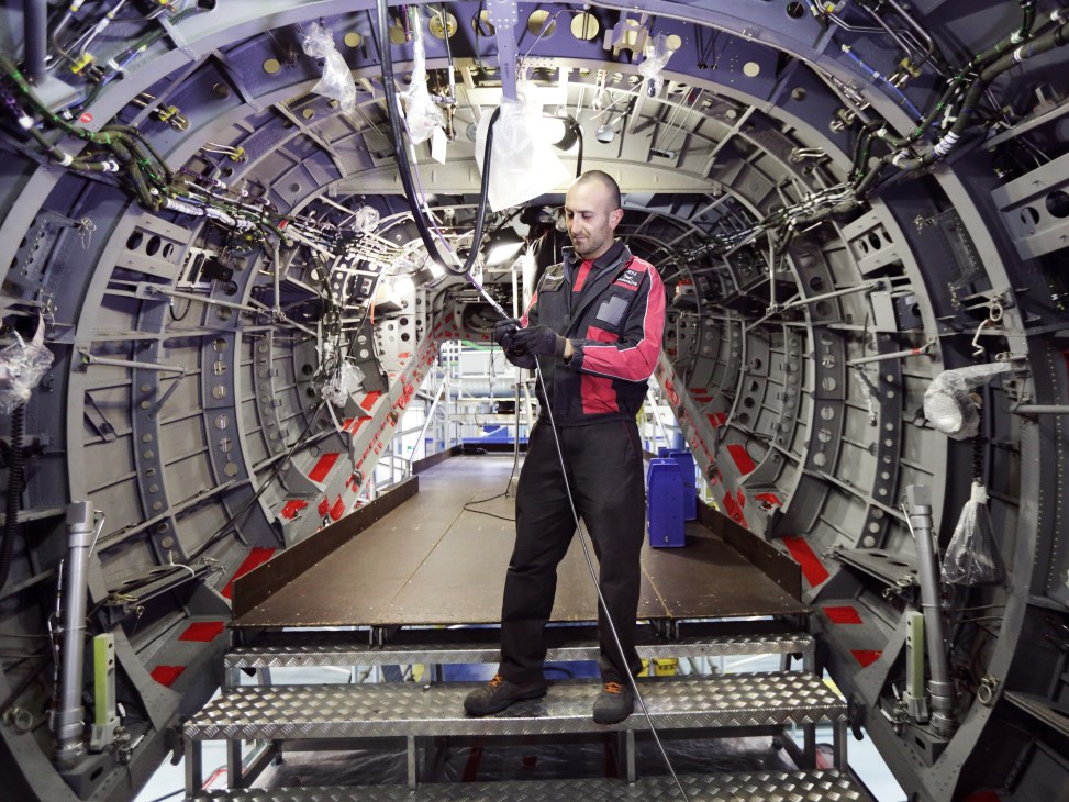 A technician inspects the interior cargo compartment of a C-27J Spartan military transport aircraft.