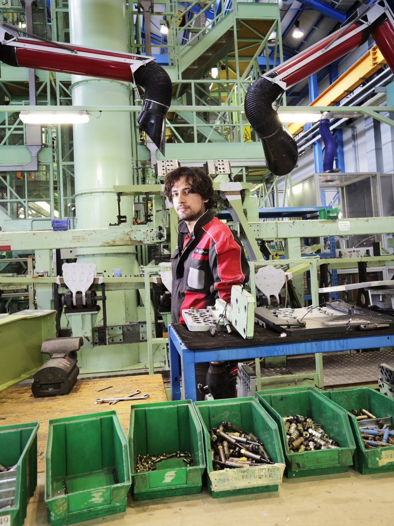 Technician working at Alenia Aermacchi aerospace manufacturing facility with aircraft components and machinery.