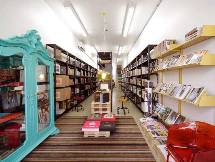 Interior of Freebook bookshop in São Paulo with turquoise ornate door frame, yellow shelving, and black storage units displaying books and magazines.