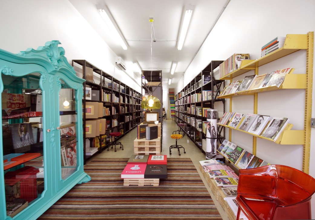 Interior of Freebook bookshop in São Paulo with turquoise ornate door frame, yellow shelving, and black storage units displaying books and magazines.