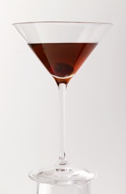 Rob Roy cocktail in a martini glass with deep red liquid against white background.