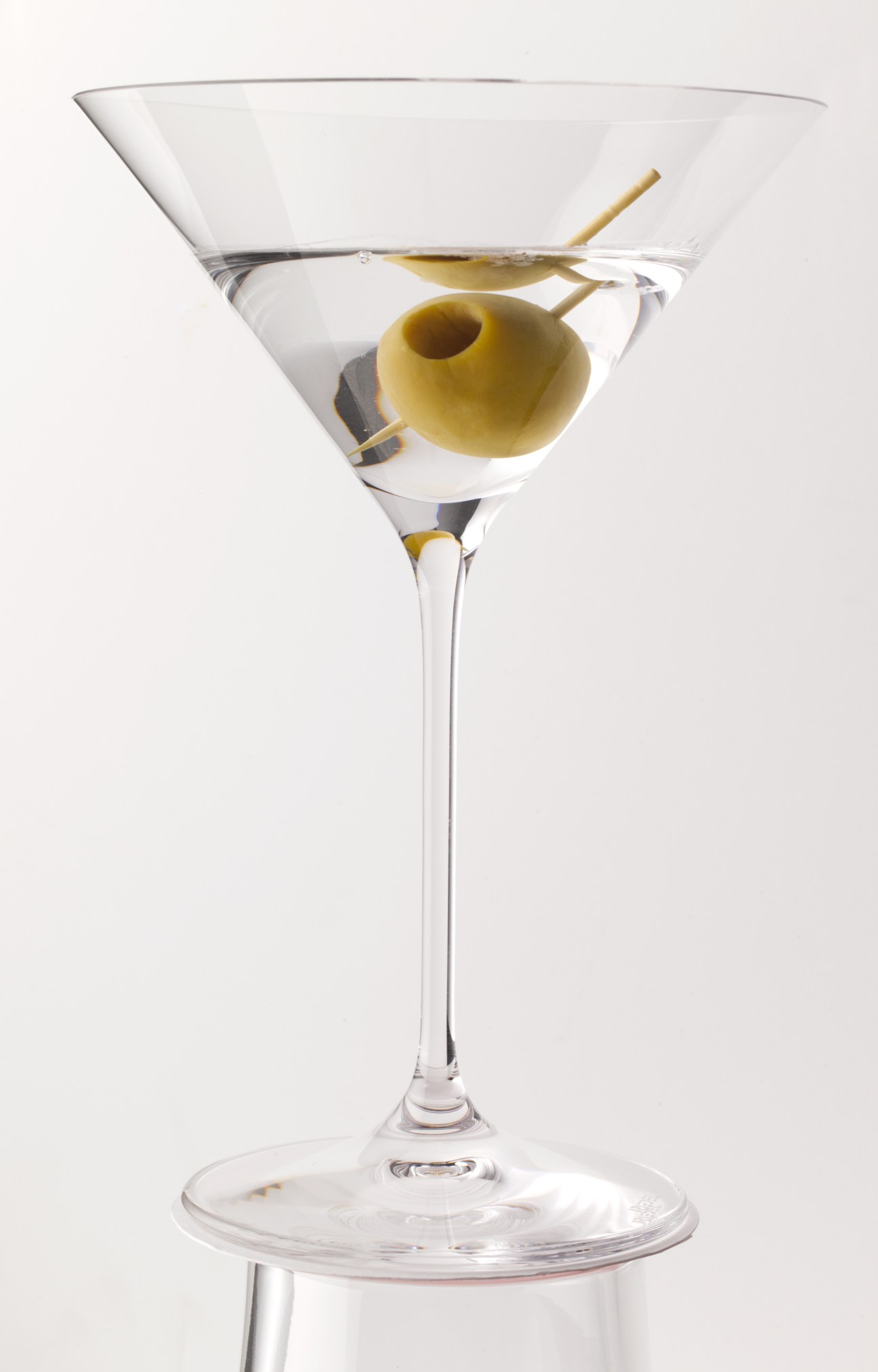 A Dry Martini cocktail in a martini glass garnished with a green olive on a pick.