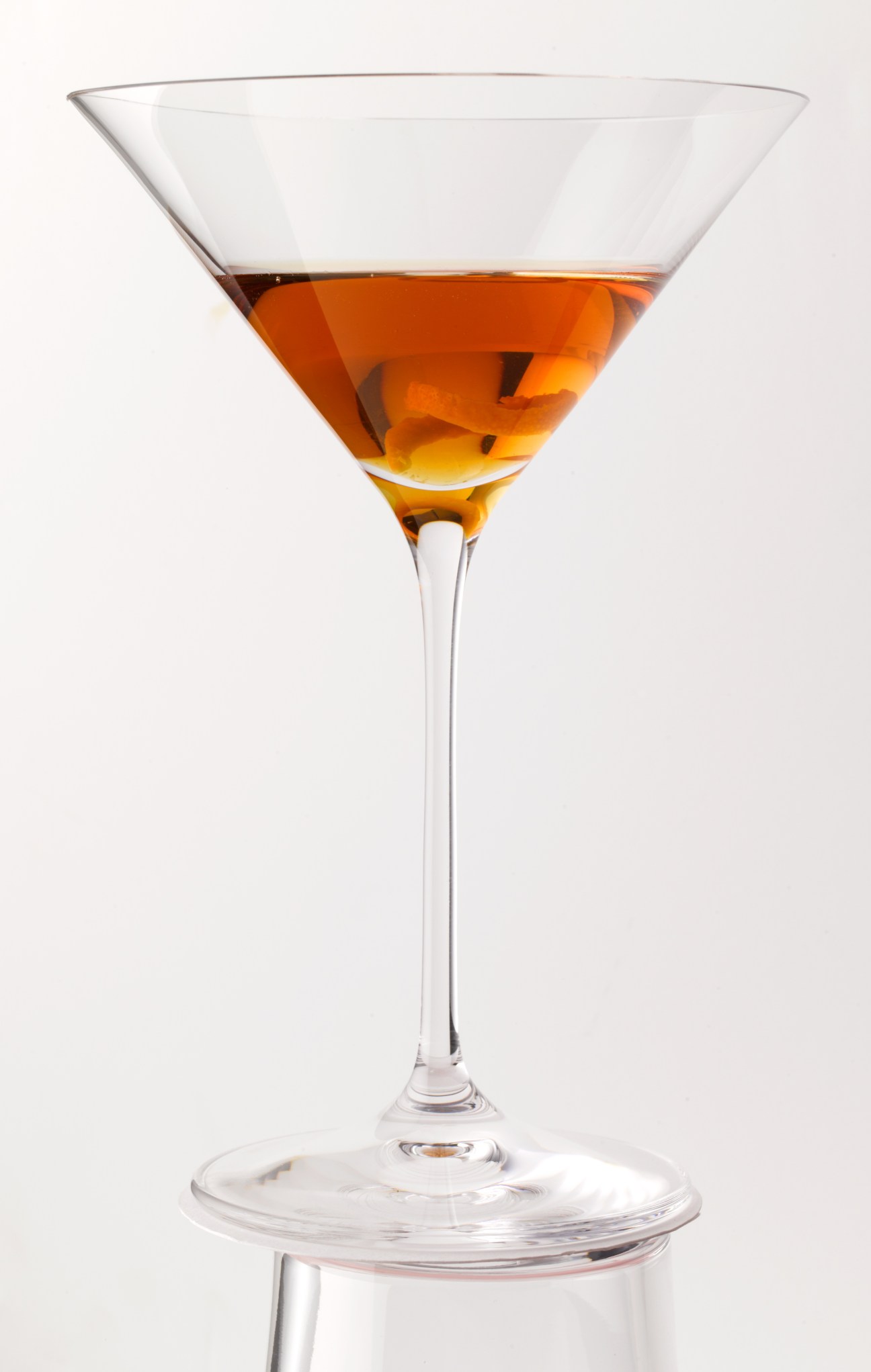 Hearst Cocktail in a martini glass with amber liquid and citrus peel garnish.