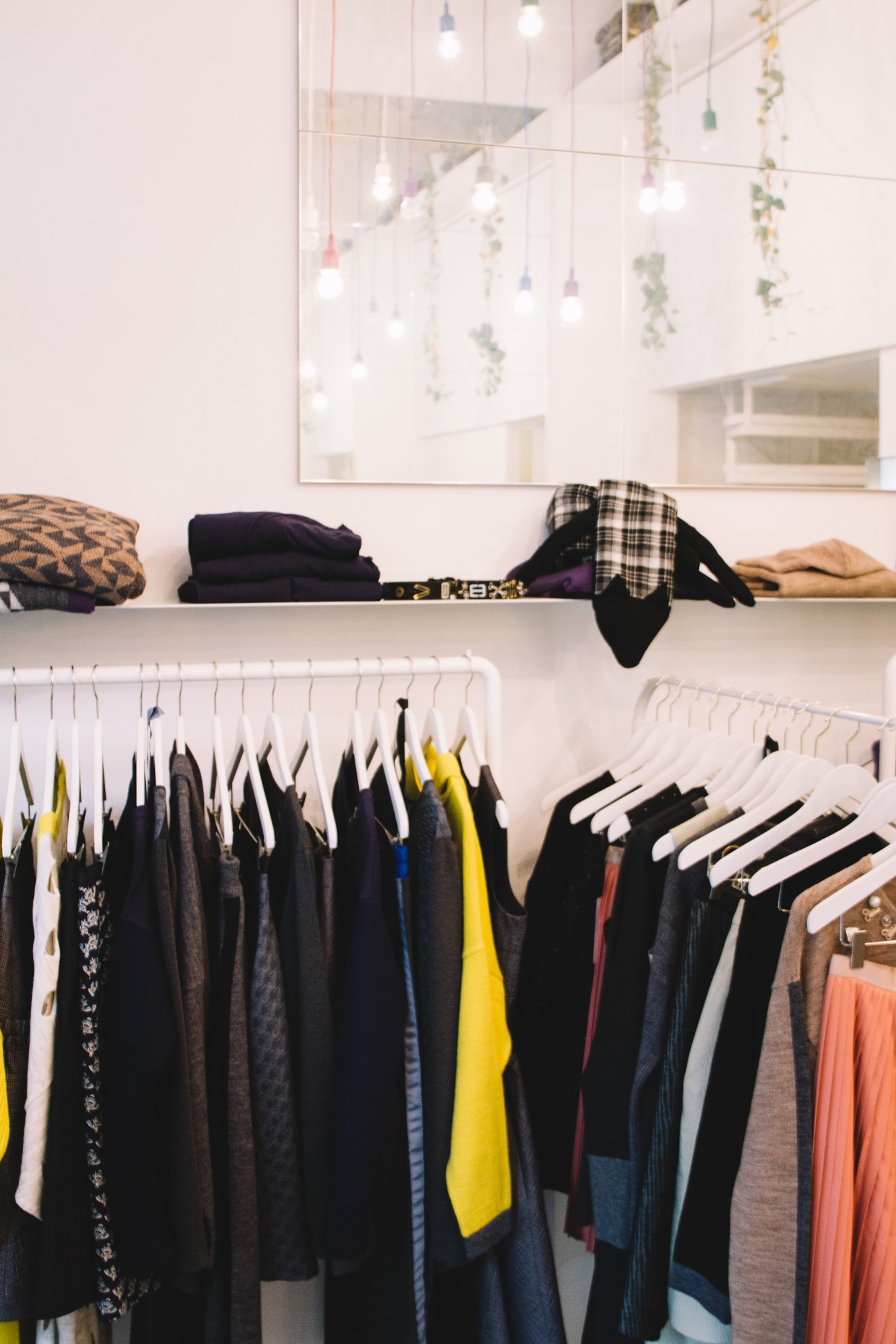 Almira Sadar fashion boutique interior with colorful clothing on hangers and folded garments on shelves.