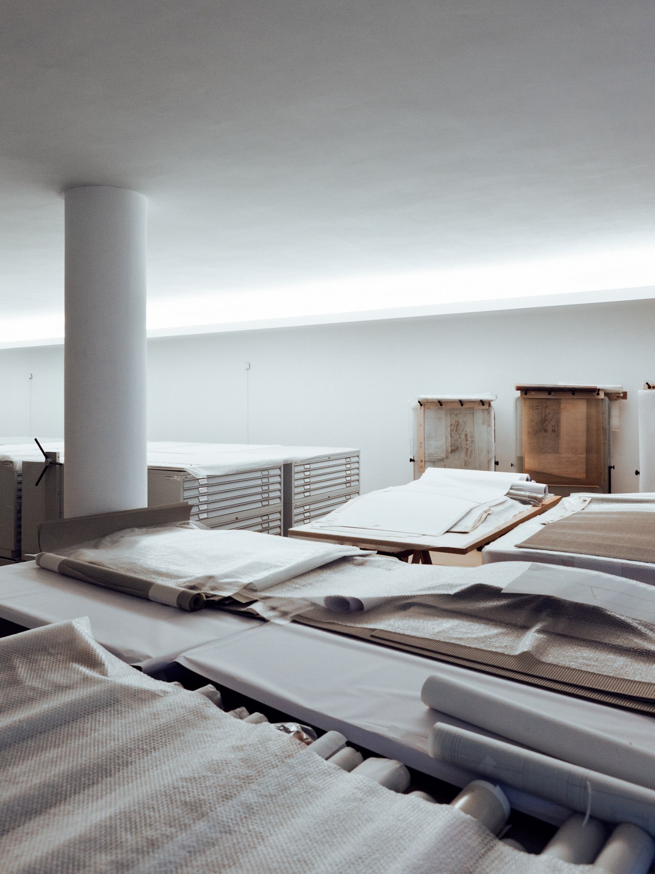 Archive room with rolled architectural plans, wooden storage cabinets, and a cylindrical column in Álvaro Siza's office building.
