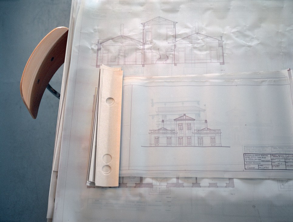 Architectural drawings and a curved wooden model on a desk showing refurbishment plans for a municipal building.