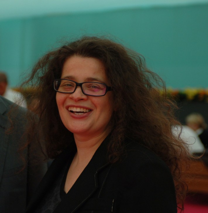 Amanda Sharp, co-director of Frieze Art Fair, smiling at camera wearing glasses and black jacket.