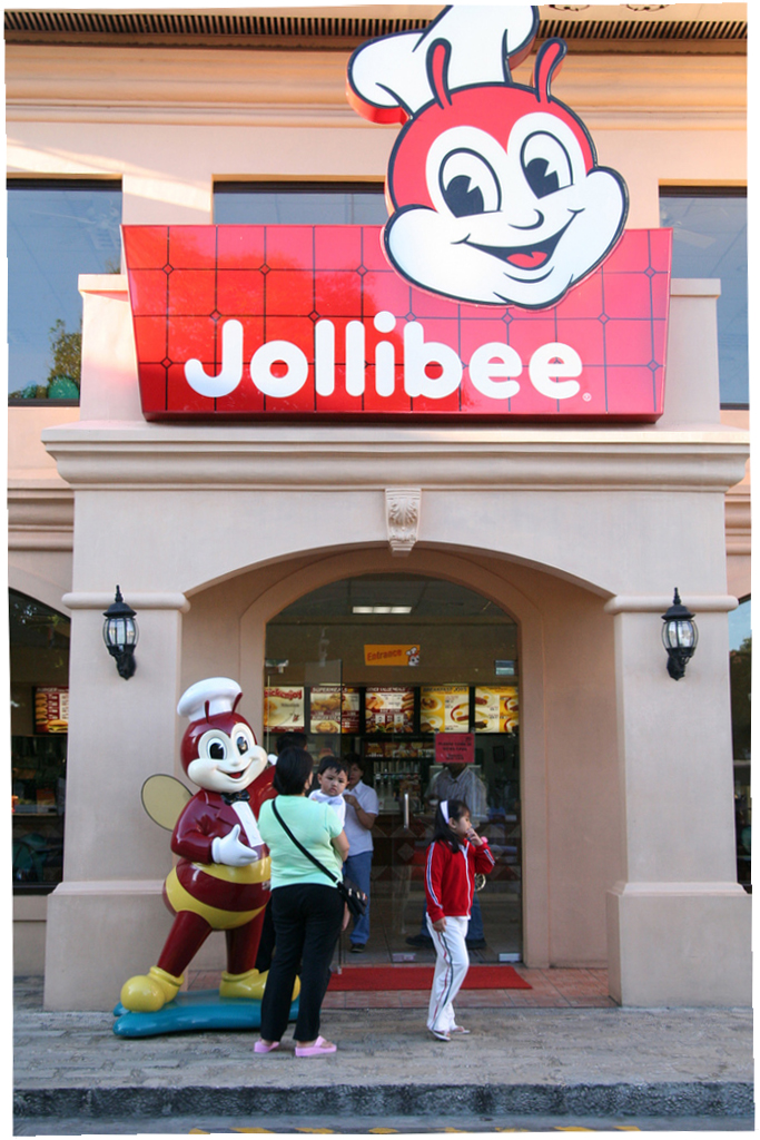 Jollibee fast-food restaurant storefront with iconic bee mascot and signage.