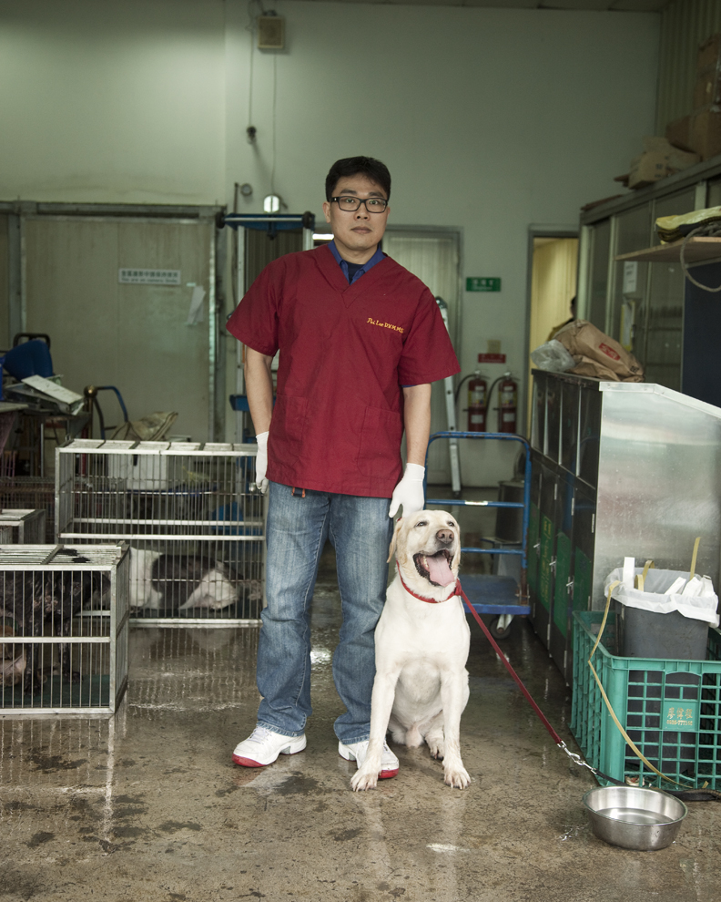 Li Jian-Pei stands with a white dog on a leash inside Taipei Animal Shelter.