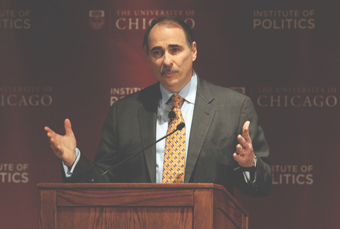 Man in gray suit speaking at podium with University of Chicago Institute of Politics backdrop