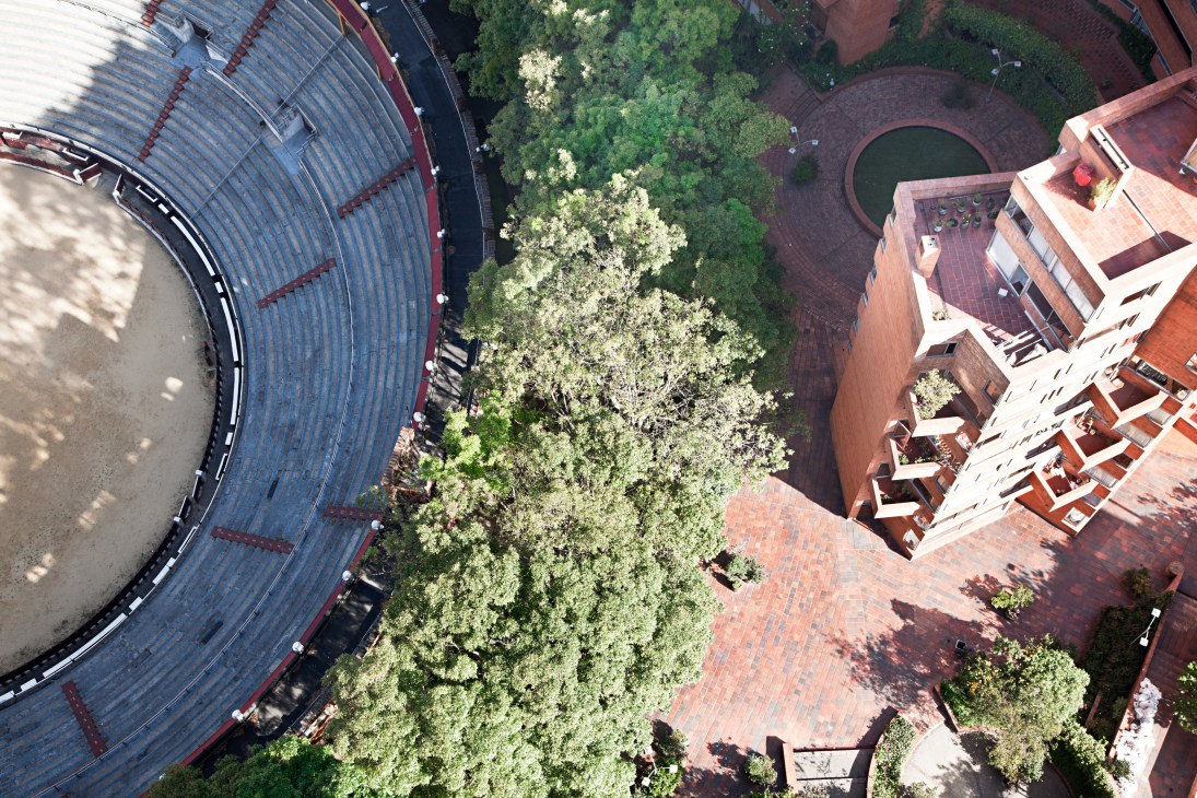 Aerial view from a high-rise apartment showing the bullring, green spaces, and surrounding Bogotá buildings below.