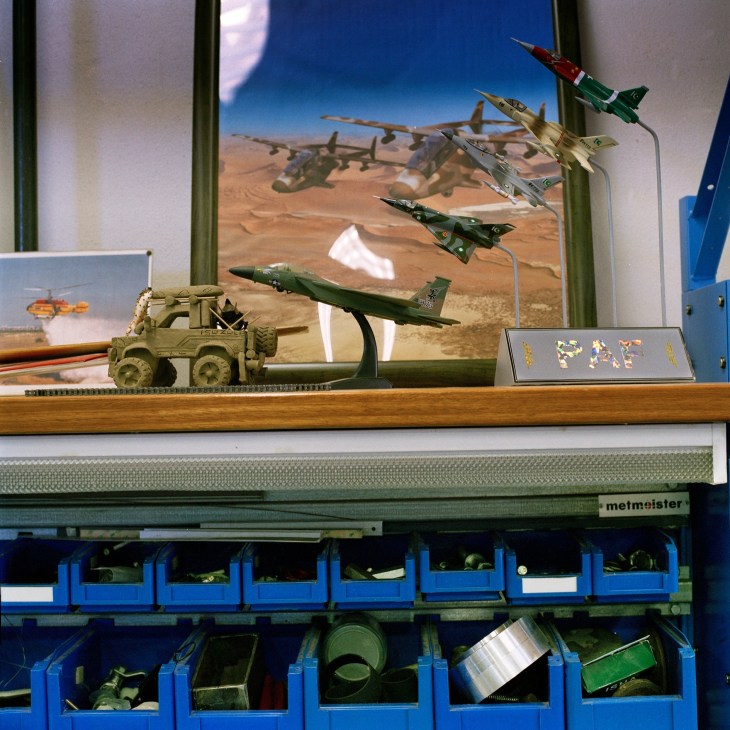 Model military aircraft and vehicles displayed on a wooden workbench at Aerosud.