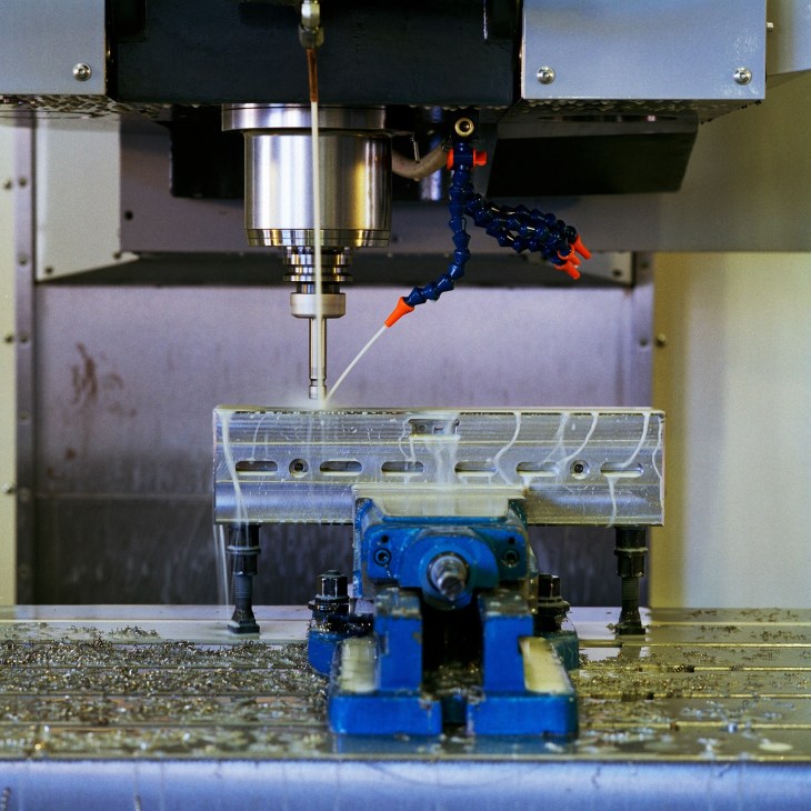 CNC machine with metallic spindle and blue mechanical components at Aerosud manufacturing facility.