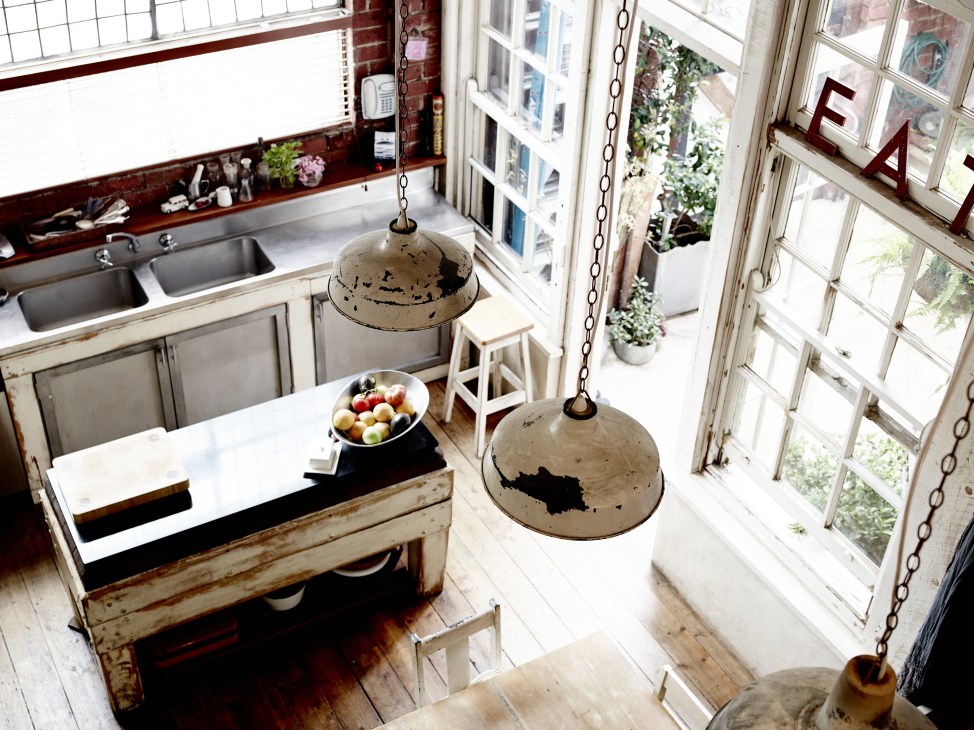 Artist Adriane Strampp's renovated loft kitchen with industrial pendant lights and large windows overlooking a courtyard.