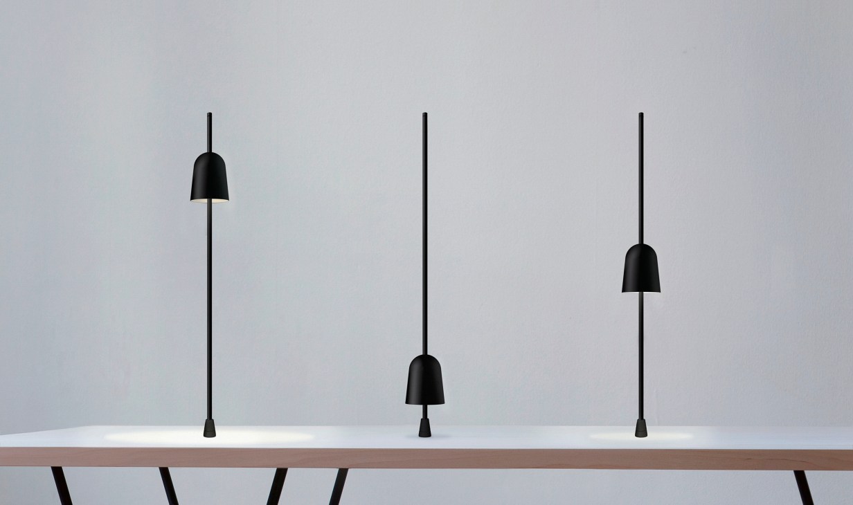 Three black pendant lights with bell-shaped shades and thin stems displayed on a shelf.