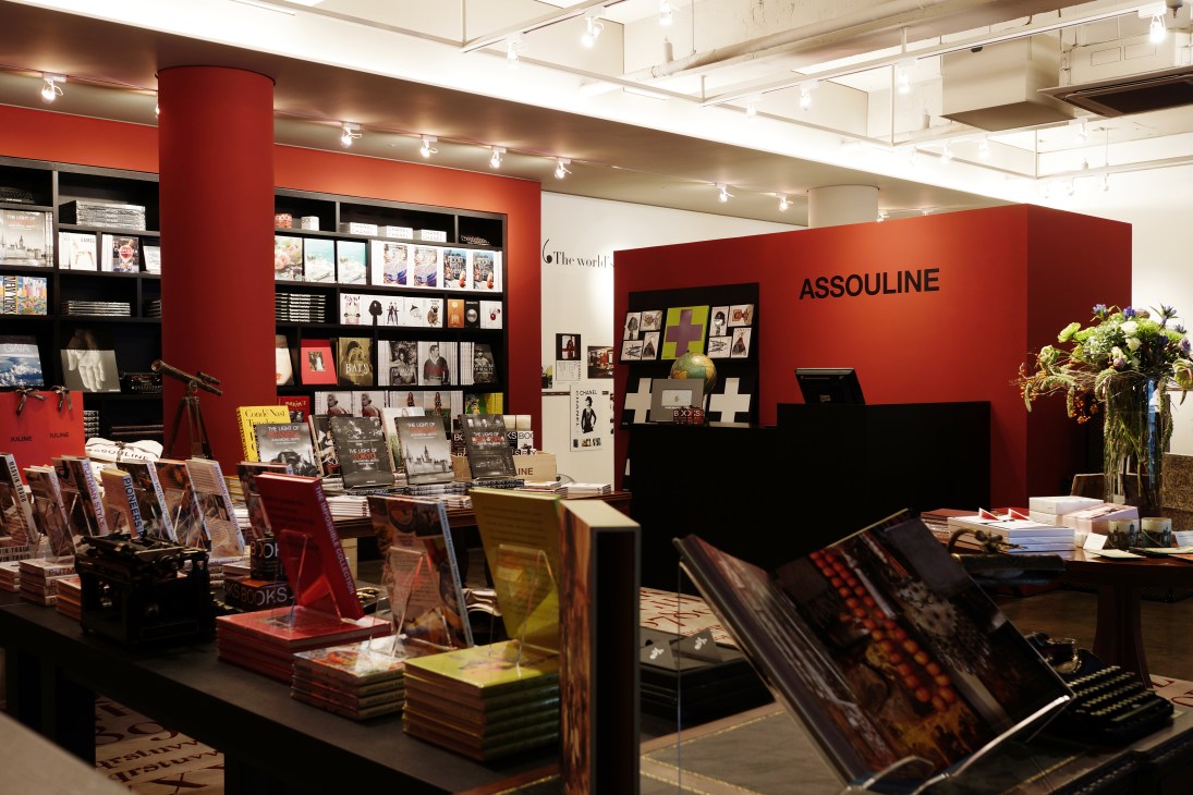 Assouline bookstore in Seoul's Gangnam district with scarlet walls, black shelving, display tables of luxury books, and fresh flowers.