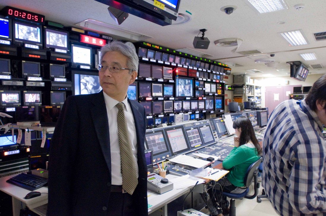 Tamaki Imai, NHK executive managing director, stands in a broadcast control room with multiple monitors and equipment.